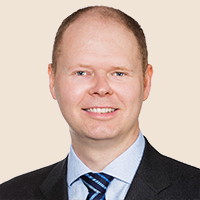 Professional headshot of a smiling man in a suit and tie.