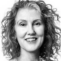 Portrait of a woman with curly gray hair smiling warmly.