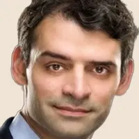 Headshot of author and professor, Sendhil Mullainathan, smiling slightly.