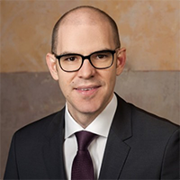 Professional man in glasses and suit, smiling confidently.