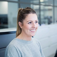 Smiling woman in office setting. Managing an Outlook signature manager.