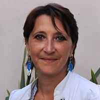 Portrait of a smiling woman with short dark hair and blue earrings.