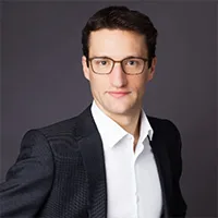 Professional headshot of a man wearing glasses and a suit jacket