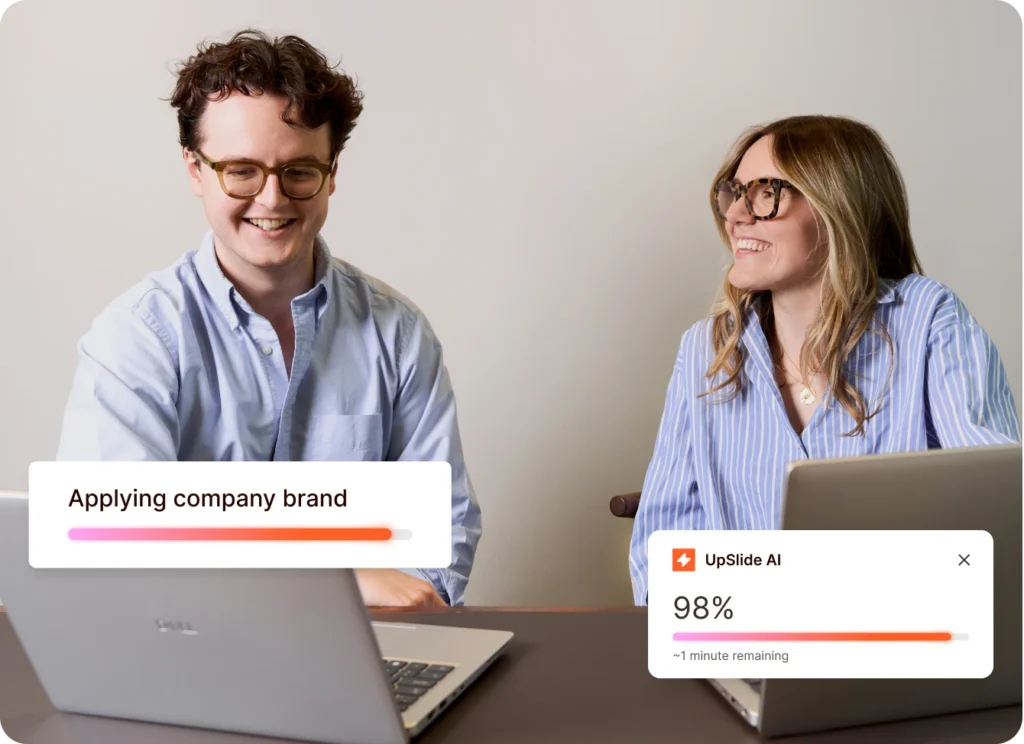 Two colleagues working on laptops, applying company brand. Team collaborating on branding strategy.