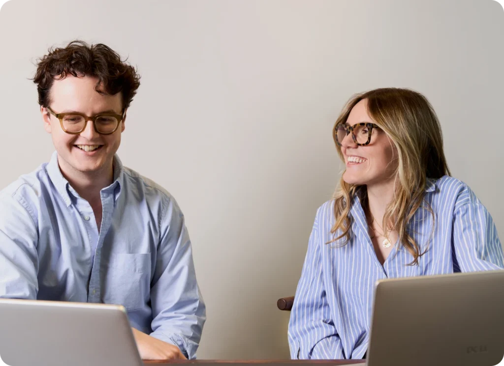 Two UpSlide team members smiling and working on laptops.
