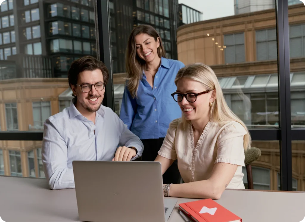 Team collaborating on a laptop, learning about UpSlide.