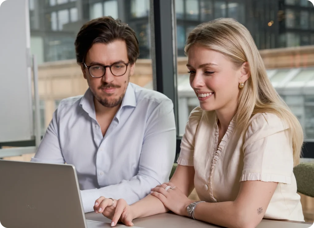 Two colleagues collaborating on a laptop during a team meeting.