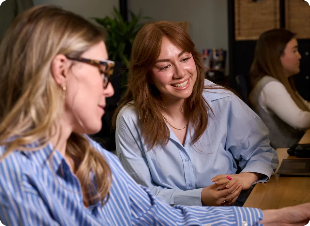Two UpSlide team members in a meeting, smiling and collaborating at a desk.