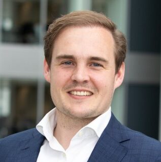 Portrait of a smiling man in a blue suit, likely a Deloitte employee